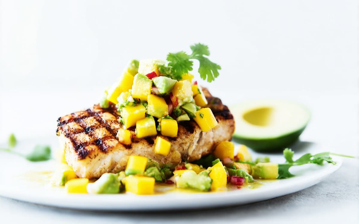 Grilled fish topped with a bright mango and avocado salsa